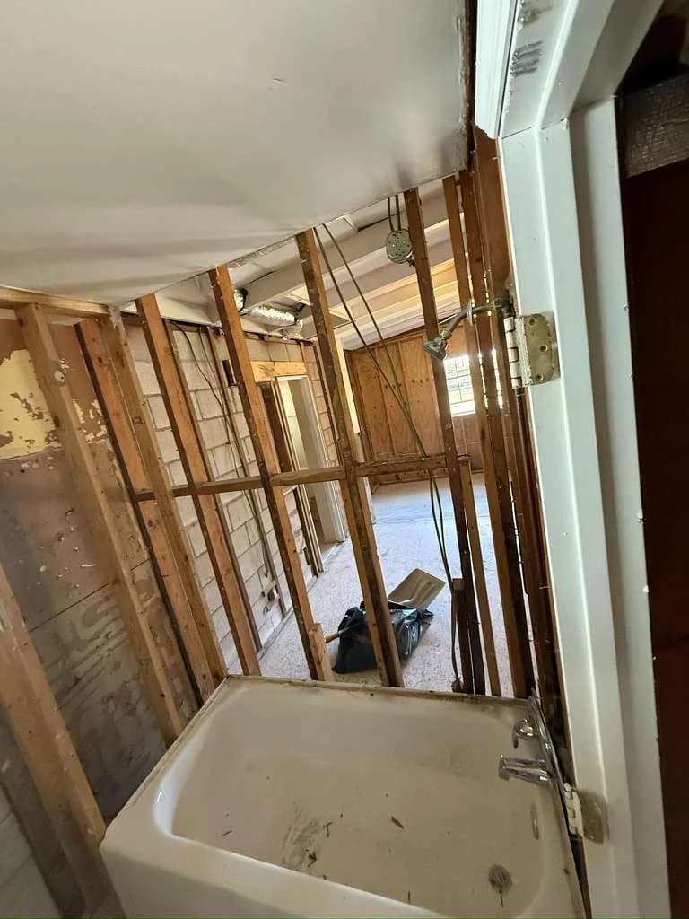 Bathroom gut renovation demolition showing exposed studs and bathtub — Orlando FL