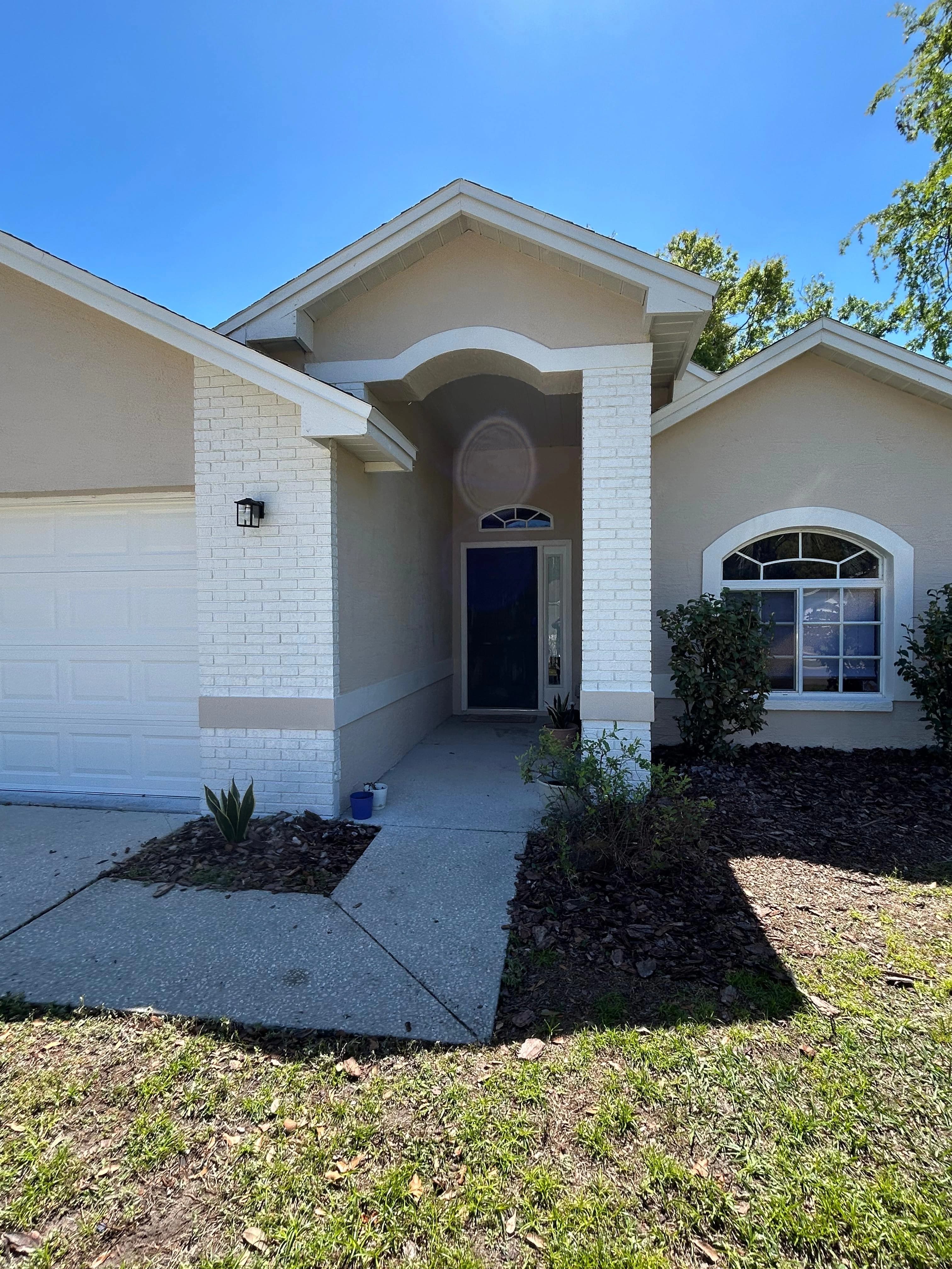 Home exterior renovation with painted stucco, arched entry and landscaping — Central Florida Renovations